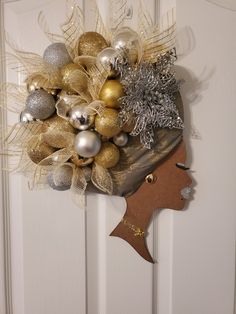 a woman's head is adorned with gold and silver christmas ornaments on a door