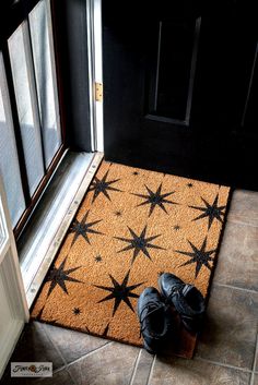 a pair of black shoes sitting on top of a door mat next to a doorway