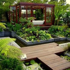 an outdoor garden with lots of plants and water features in the center, surrounded by greenery