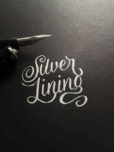 a pen writing the words silver living on a piece of black paper with white ink