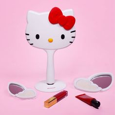 a hello kitty makeup set with lipstick and eyeliners on a pink background,