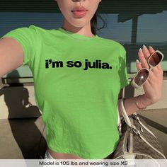 "Im So Julia Charli XCX" Graphic Slogan Printed On Aesthetic Retro Vintage 90s Y2k Baby Tee Shirt with our own unique font.  🎨 Available in White, Light Pink, Light Blue, Navy, Black. If you need a different color, please let us know! (Ash, Red, Sport Grey & Green)  🎁 Our baby tees are perfect gift for her or him offering timeless fashion and versatility that anyone will cherish. Baby tees, popular in the '90s, have short sleeves and a slightly cropped body, giving a flattering feminine shape. Y2k Fitted Crew Neck Shirt, Fitted Y2k Crew Neck Shirt, Y2k Green Tops For Streetwear, Y2k Green Graphic Print Tops, Green Graphic Print Y2k Tops, Y2k Green Top For Streetwear, Green Y2k Style Top For Streetwear, Green Y2k Graphic Print Tops, Fitted Green Y2k T-shirt