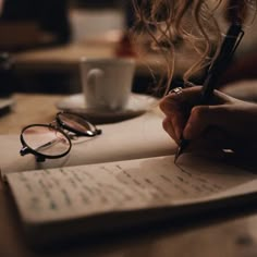 a person is writing on a piece of paper with a pen and eyeglasses