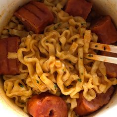 a bowl filled with noodles and meat next to chopsticks