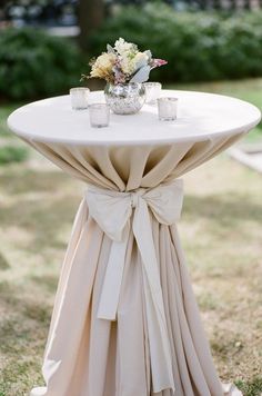 a white table topped with a vase filled with flowers next to two candles on top of it