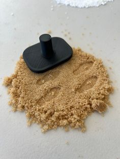 a pile of sand next to a black object on top of a white countertop