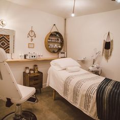 a small room with a bed, chair and shelves on the wall above it is also a hair dresser