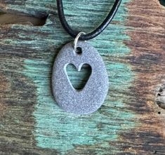 a necklace with a heart cut out of it on a wooden table next to leaves