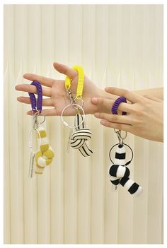 two hands are holding several different key chains