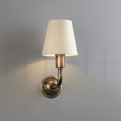 a wall light with a white shade on it's side and a gray wall in the background