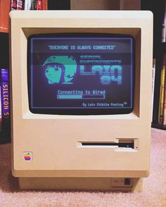 an old computer with the screen turned on sitting in front of a bookshelf