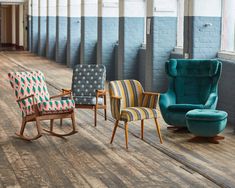 four rocking chairs lined up against a brick wall in an empty room with wood flooring