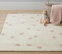 a teddy bear sitting on top of a white rug next to a basket and blanket