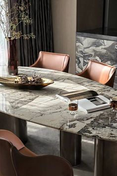 a marble dining table with leather chairs around it