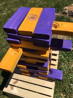 a purple and yellow bench sitting on top of a wooden pallet in the grass