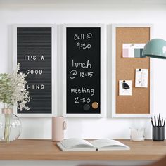 a desk with a book, vase and two framed pictures on the wall above it