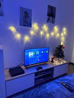 a flat screen tv sitting on top of a white entertainment center next to a christmas tree