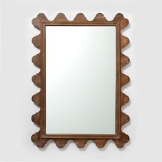 a mirror that is on the wall next to a white wall with a wooden frame