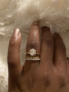 a woman's hand with a diamond ring on top of her finger and the other hand holding it