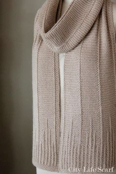 a white mannequin wearing a beige knitted scarf