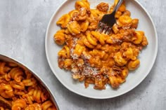 a white plate topped with macaroni and cheese next to a pot of sauce