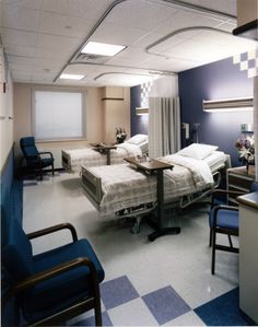 an empty hospital room with beds and chairs in the middle of the room on checkered flooring