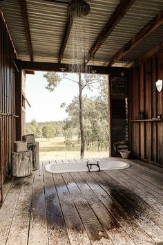 an outdoor bathtub in the middle of a wood floored room with open doors