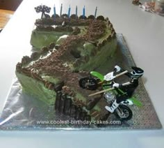 a motorcycle themed birthday cake with dirt bike on the front and side, sitting on top of a table