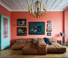 a living room with orange walls and pictures on the wall, including a brown couch