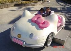 a hello kitty car is parked on the side of the road with people in it