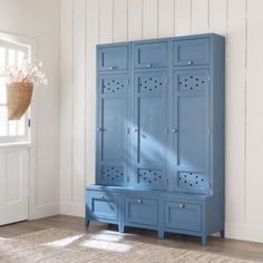 a blue armoire sitting in the corner of a room next to a rug and window