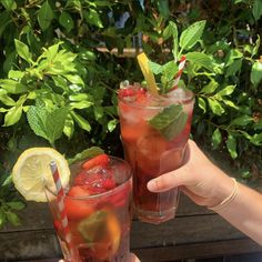 two people holding up glasses filled with drinks