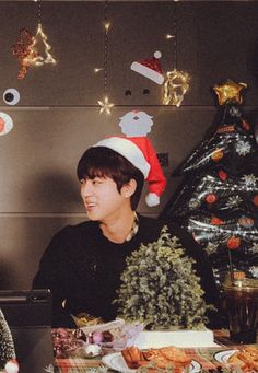 two people sitting at a table with food in front of christmas decorations on the wall