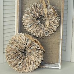 two pieces of driftwood are displayed in an old window frame with burlap