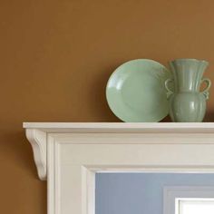 two green vases sitting on top of a white mantle in front of a mirror