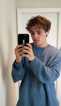 a young man taking a selfie in front of a mirror with his cell phone