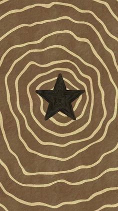 a black star sitting on top of a brown and white striped rug with wavy lines in the background