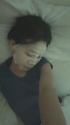 a woman laying in bed with her face covered by plastic wrap and covering her eyes