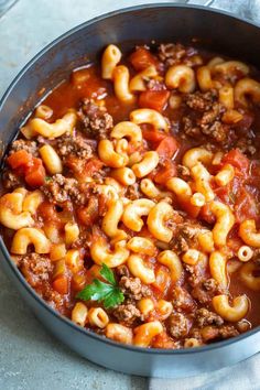 a pot filled with pasta and meat in tomato sauce on top of a table next to a napkin