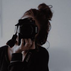 a woman taking a photo with her camera in front of her face and holding it up to the side