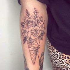 a woman's leg with flowers and an ice cream cone tattoo on her arm