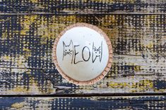 a small white bowl with writing on it sitting on top of a wooden table next to a wall