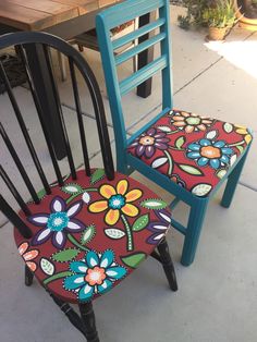 two chairs with colorful flowers painted on them, one is blue and the other is red