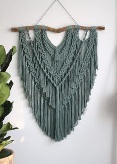 a green wall hanging with fringes on it