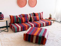 a multicolored striped couch and ottoman in a living room with two round wall hangings