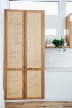 a kitchen with white walls and wooden cabinets in the corner, along with a plant on the counter