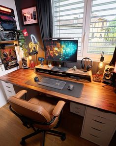 a computer desk with a keyboard, mouse and monitor on it in front of a window