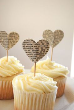 two cupcakes with heart shaped toppers sitting on a plate