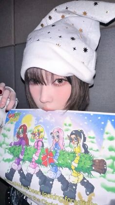 a woman holding up a christmas card with cartoon characters on it's front cover