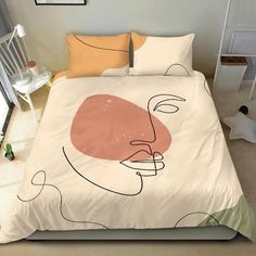 a bed covered in a pink and orange comforter next to a white table with a potted plant on it